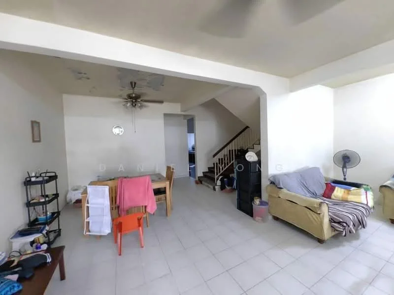 Living features: white painted walls, ceiling fan, tile flooring, sofa in beige, wooden dining table with chairs, decorative wall clock, open layout, staircase in background, small side table, laundry drying rack, orange plastic chair, floor fan.