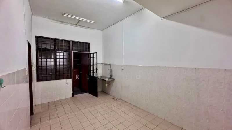 Room features: white painted walls, tile flooring, single-bowl stainless-steel sink, wooden door, grilled window, fluorescent lighting, corner wall with tiled cladding, open layout.