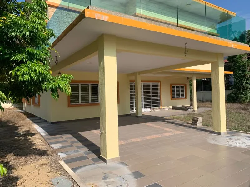Exterior type: detached bungalow; features: yellow painted facade, flat roof, covered porch area, large windows with horizontal slats, paved walkway, manicured lawn, surrounding greenery, balcony with glass railing, outdoor lighting fixtures; style: modern.