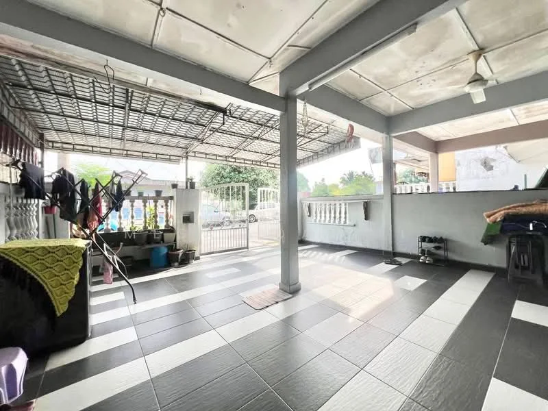 Exterior type: linked terrace house; features: covered porch area, grey tiled flooring, white painted walls, metal gate at entrance, open space with natural light, clothes drying rack, ceiling fan, fenced perimeter, manicured garden visible in background; style: modern.
