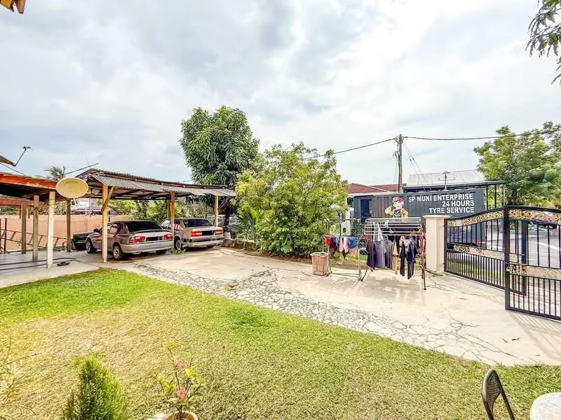 Exterior type: detached bungalow; features: manicured lawn, paved driveway, carport with roof, two parked cars, clothesline with hanging clothes, fenced perimeter, mature trees, street view, tyre service signage; style: traditional.