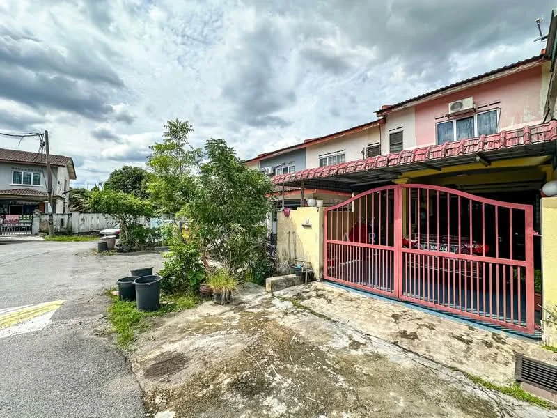 Exterior type: linked terrace house; features: red metal gate, driveway with concrete surface, manicured shrubs, potted plants, two-storey structure, roof with overhang, exposed brick facade, parking space visible, surrounded by residential area, cloudy sky; style: modern.