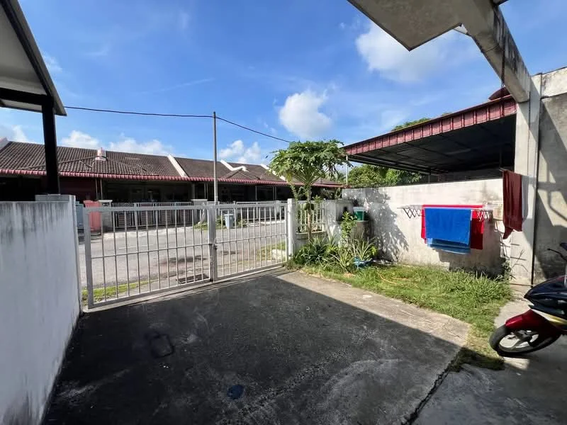 Exterior type: linked terrace house; features: metal gate, concrete driveway, manicured lawn, mature trees, laundry area with hanging clothes, covered carport, paved walkway, surrounding residential area, clear blue sky; style: modern.