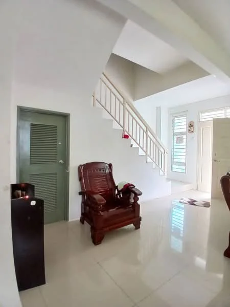 Room features: white painted walls, cream tiled flooring, staircase with wooden railing, green door, wooden armchair, decorative wall art, large windows with natural light, area rug; style: modern.