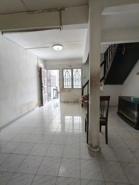 Room features: white painted walls, tile flooring, single ceiling light fixture, staircase, wooden chair, large window with metal grille, open layout, corner for a TV console.