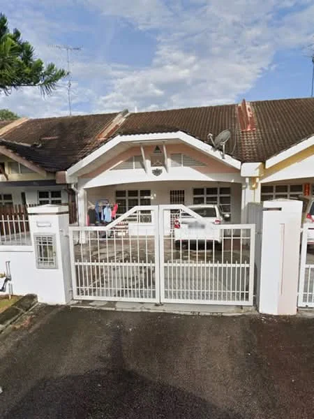 Exterior type: linked terrace house; features: white painted facade, pitched tile roof, single-storey, front gate with metal grille, driveway with interlocking pavers, visible car parked in driveway, manicured lawn, mature trees, satellite dish on roof, outdoor clothes drying area; style: traditional.