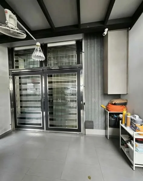 Room features: sliding glass door with horizontal metal bars, grey tiled flooring, exposed beam ceiling, ceiling fan with light, built-in cabinet with wood finish, open shelving unit, various cleaning supplies and tools on shelving unit, decorative wall paneling; style: modern.