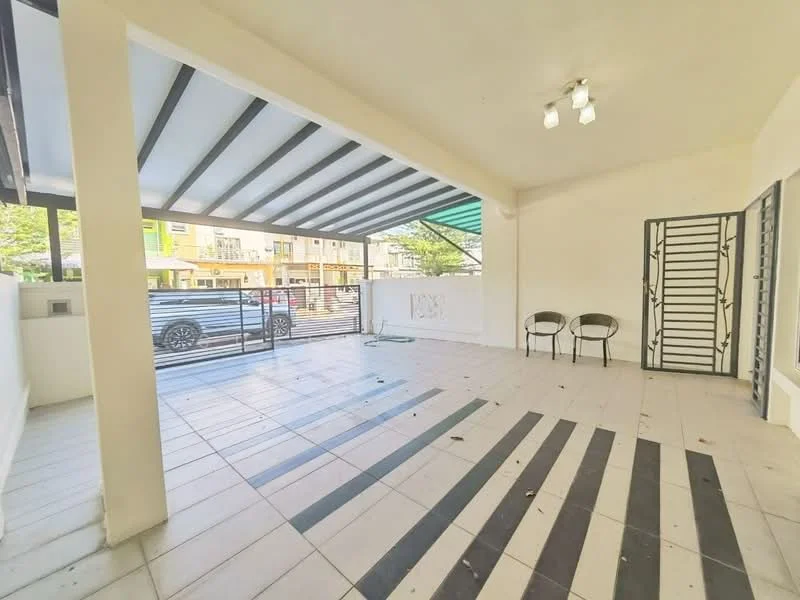 Exterior type: linked terrace house; features: covered porch area, striped floor tiles, white painted walls, exposed beams on ceiling, two outdoor chairs, security grille, green awning, driveway visible, surrounded by residential buildings; style: modern.