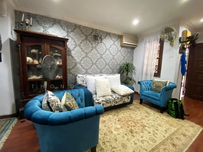 Living features: blue upholstered armchairs, sofa with floral pattern upholstery, decorative throw pillows, wooden display cabinet, wall-mounted air conditioning unit, green indoor plant, wooden flooring, area rug with intricate pattern, wall with damask pattern wallpaper, ceiling fan, decorative wall sconce; style: traditional.