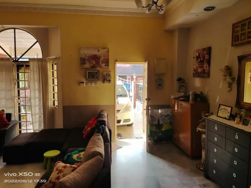 Living features: grey L-shape sectional sofa, marble flooring, yellow painted walls, decorative wall mirror, framed artwork on walls, window with sheer curtains, wooden side table, black storage cabinet, open doorway leading outside, visible car in driveway; style: contemporary; view: driveway.