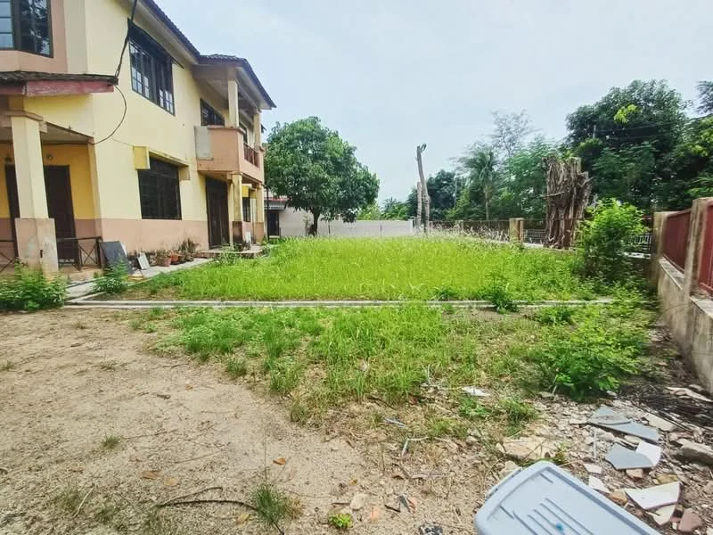 Exterior features: two-storey building, overgrown grass, dirt ground, surrounding trees, fenced perimeter, adjacent structure, open space, scattered debris.