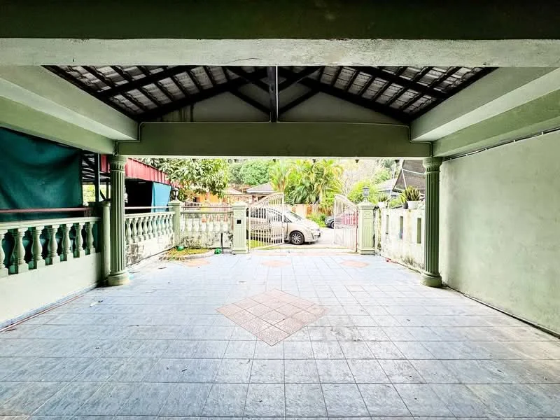 Exterior type: car porch; features: open-air car porch, green painted walls, grey tiled flooring, exposed beam ceiling, decorative columns, manicured garden view, driveway access, surrounded by fencing; style: traditional.