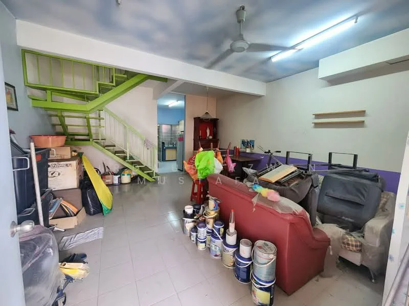 Living features: white painted walls, grey tiled flooring, 5-blade ceiling fan, sofa in red upholstery, coffee table, paint cans, decorative items, staircase with green railing, open layout, natural light from windows.