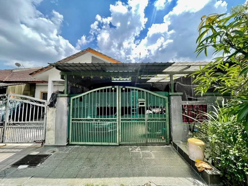 Exterior type: linked terrace house; features: green metal gate, covered car porch, grey tiled driveway, manicured garden, paved walkway, single-storey, roof over car porch, surrounded by greenery, residential neighborhood, visible sky with clouds; style: modern.