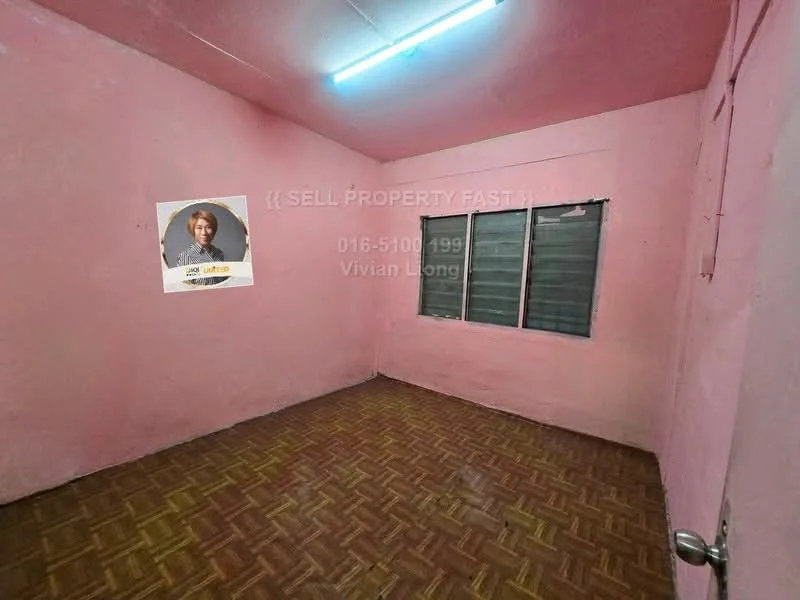 Room features: pink painted walls, vinyl flooring, two windows with grilles, ceiling light fixture, door with handle.