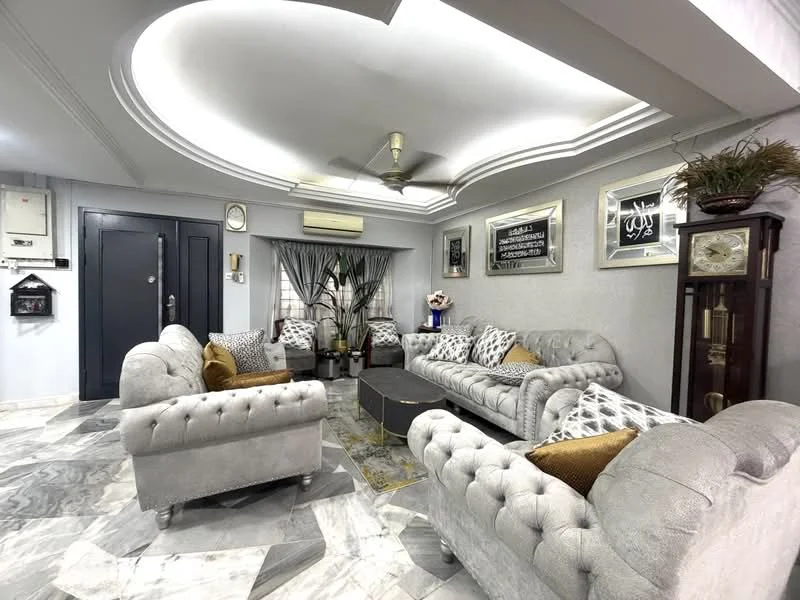 Living features: 5-blade ceiling fan with light, tray ceiling, grey velvet tufted sofa, 2-seater grey velvet armchair, decorative throw pillows, coffee table with gold accents, marble flooring with grey and white patterns, wall-mounted artwork, curtains with geometric pattern, wall clock, potted plants, framed decorative mirrors; style: modern.