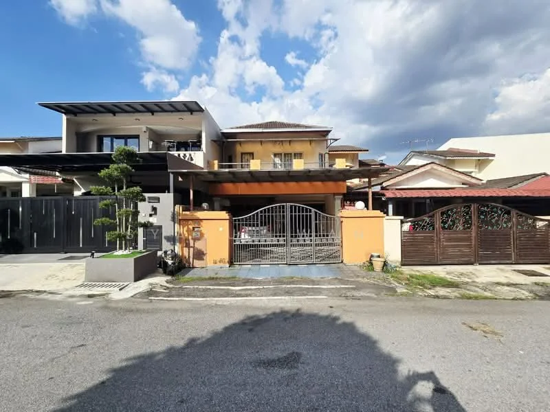 Exterior type: detached bungalow; features: two-storey structure, orange painted facade, metal gate, manicured garden with small trees, covered car porch, sloping roof, balcony on the upper floor, driveway with interlocking pavers, surrounded by residential neighborhood, visible neighboring houses; style: modern.