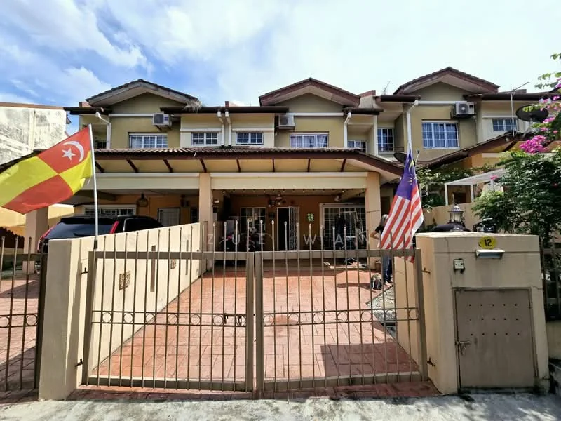 Exterior type: linked terrace house; features: two-storey building, cream painted facade, red tiled roof, front porch with tiled flooring, metal gate, two visible air conditioning units, two flags displayed, landscaped garden with flowering plants, driveway with interlocking pavers; style: modern.