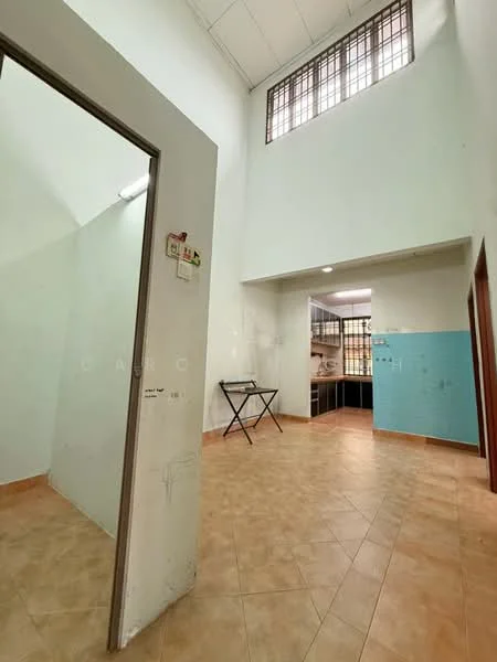 Room features: high ceiling, tiled flooring in beige, white painted walls, blue accent wall, window with metal grille, doorway leading to another room, open layout, kitchen area visible in background; style: modern.