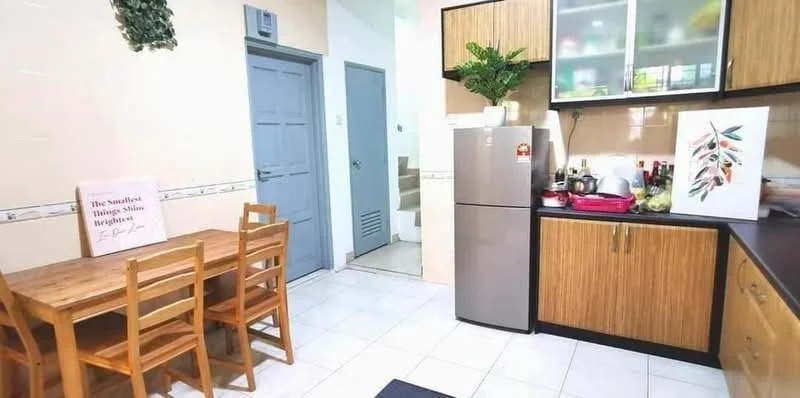 Kitchen features: brown wooden cabinetry, black countertop, stainless-steel fridge, built-in sink, chrome faucet, white tiled backsplash, ceramic tile flooring, dining table with four wooden chairs, wall-mounted shelves, decorative plant on shelf, doorway leading to hallway, light-colored walls; style: modern.