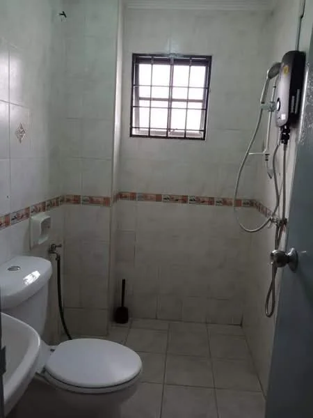Bathroom features: white tiled walls, light grey tiled flooring, one-piece toilet, chrome basin mixer faucet, shower with handheld showerhead, window with metal grille, toilet brush holder, decorative tile border.