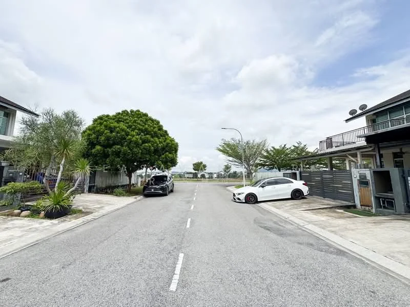 Exterior features: paved road, landscaped greenery, mature trees, two parked cars, residential buildings in background, open sky, curbside drainage; style: modern.