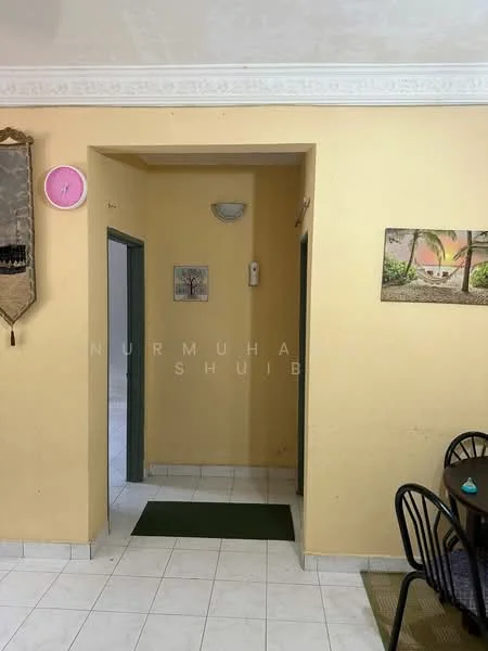 Room features: yellow painted walls, white ceiling with crown moulding, white tiled flooring, doorway leading to another room, wall-mounted light fixture, wall clock, green door frames, green mat at entrance.