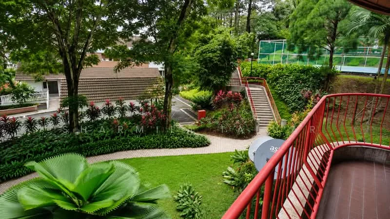 Exterior type: landscape garden; features: manicured lawn, mature trees, tropical landscaping, flower beds with colorful plants, paved walkway, staircase leading to upper level, tennis court visible in background, red railing on balcony, surrounded by greenery; style: tropical-modern.