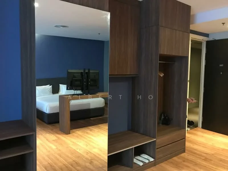 Room features: wooden flooring, blue painted walls, built-in wardrobe with wood finish, open shelving, hanging space for clothes, two beds visible in background, television on stand, doorway leading to another room, light fixture on ceiling; style: modern.