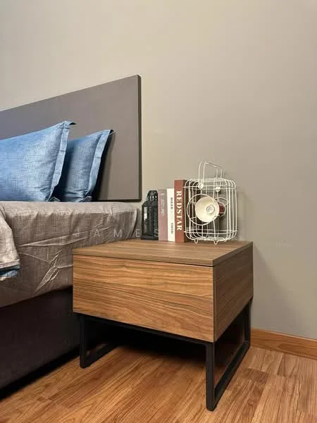 Bedroom features: queen-size bed with grey bedding, upholstered headboard, wooden bedside table with black metal legs, table lamp with wire cage design, stack of books on bedside table, wooden flooring, grey painted walls; style: modern.