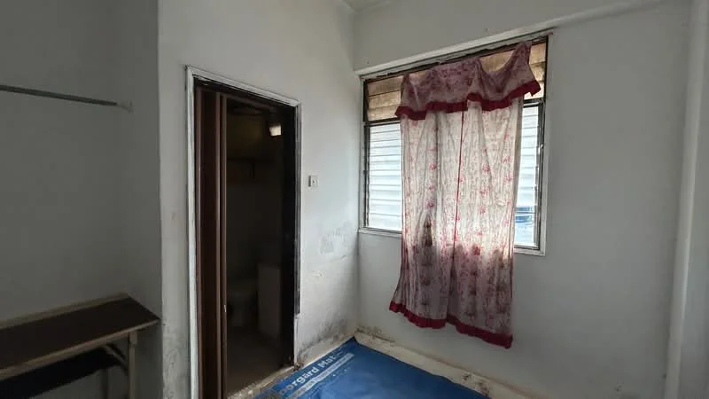 Room features: white painted walls, vinyl flooring, two windows with sheer curtains, door leading to another room, basic ceiling light fixture, corner shelf, blue mat on the floor; style: minimalist.