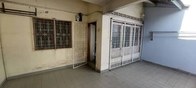 Room features: grey tiled flooring, two metal grilles on windows, white walls with some wear, doorway leading to another room, metal railing on one side, exposed ceiling beams, natural light from windows, corner wall with paint peeling.