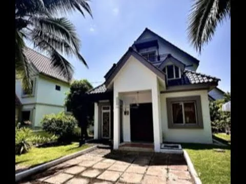 Exterior type: detached bungalow; features: white painted facade, pitched tile roof, manicured lawn, paved walkway, tropical landscaping, front porch, large windows, surrounded by palm trees; style: tropical-modern.