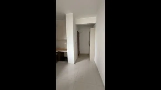 Room features: white painted walls, light grey floor tiles, open layout, doorway leading to another room, built-in cabinetry, neutral color scheme, natural light from adjacent room; style: minimalist.
