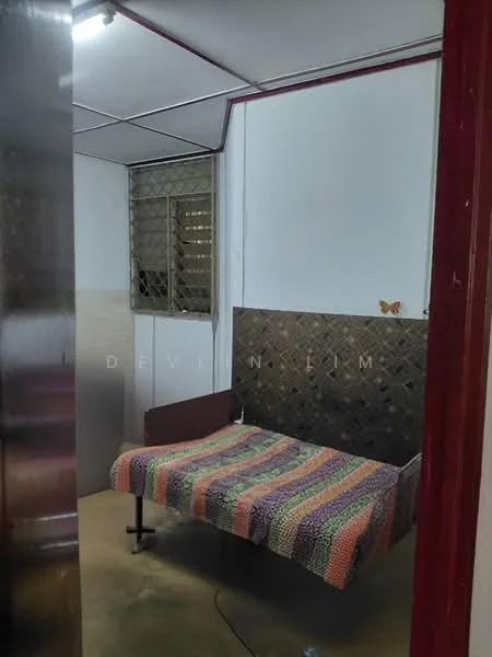 Room features: single bed, colorful knitted blanket, metal headboard, window with metal grille, plain white walls, concrete flooring, ceiling with fluorescent lighting, corner wall with a butterfly decoration; style: minimalist.