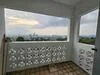 Room features: decorative block wall, tiled flooring, large window with city view, open balcony space, white painted walls, door leading outside; style: modern; view: city.