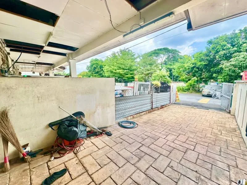 Exterior features: paved driveway, concrete wall, metal gate, surrounding greenery, outdoor storage items, partially covered area, visible vehicle, open space.