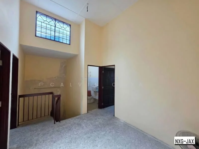 Room features: light yellow painted walls, grey flooring, wooden staircase, stained glass window, doorway leading to bathroom, doorway leading to another room, high ceiling, no visible furniture.