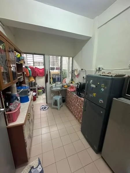 Kitchen features: ceramic tile flooring, white painted walls, wood cabinetry with glass-front upper cabinets, stainless-steel fridge, built-in countertop with sink, kitchen appliances including kettle and rice cooker, open shelving, window with sheer curtains, plastic stool, laundry area with hanging clothes, decorative wall tiles, multiple storage baskets.