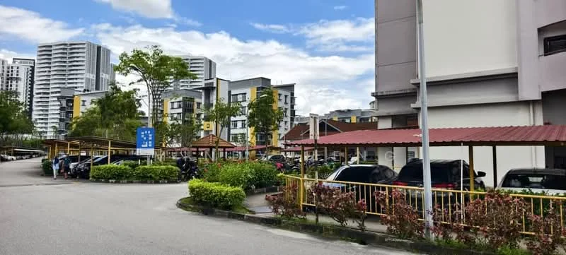 Exterior type: low-rise apartment block; features: covered parking with awnings, manicured landscaping, paved driveway, surrounding greenery, multiple-storey buildings, urban context with nearby high-rises; style: modern.