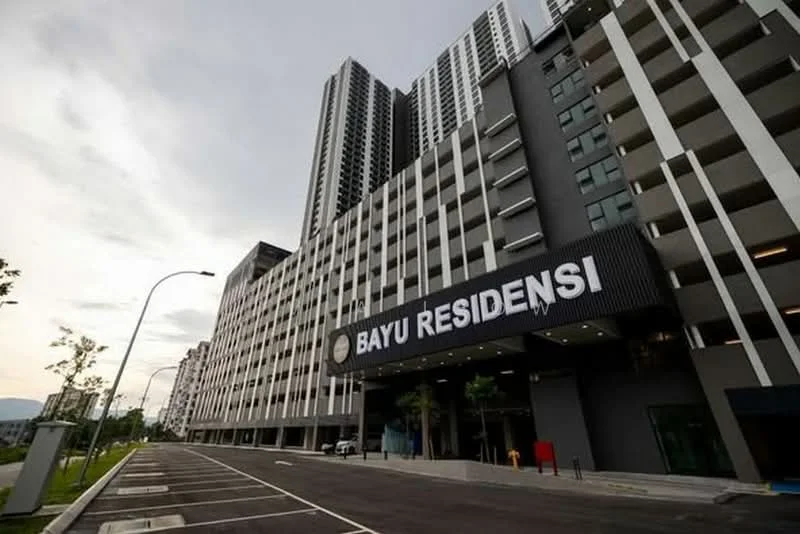 Exterior type: high-rise condominium; features: glass curtain wall, black metal facade, signage with 'BAYU RESIDENSI', multi-storey car park, landscaped greenery, paved driveway, street lighting, surrounding trees; style: modern.