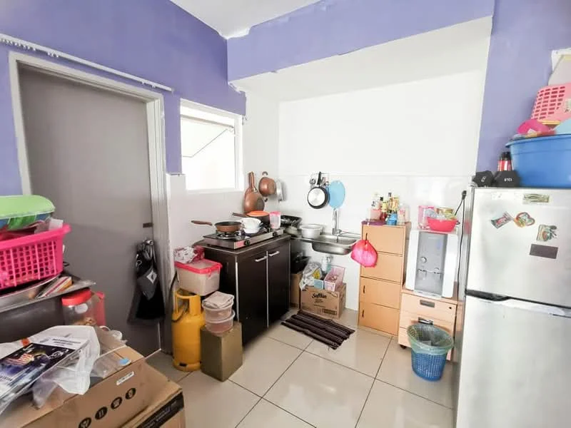 Kitchen features: purple painted walls, white tiled backsplash, ceramic tile flooring, stainless-steel sink, chrome pull-down faucet, black kitchen cabinets, wooden countertop, freestanding fridge, gas stove with 4 burners, various kitchen utensils and containers, plastic storage bins, stacked boxes, open shelving, kitchen cart, wall-mounted hooks.