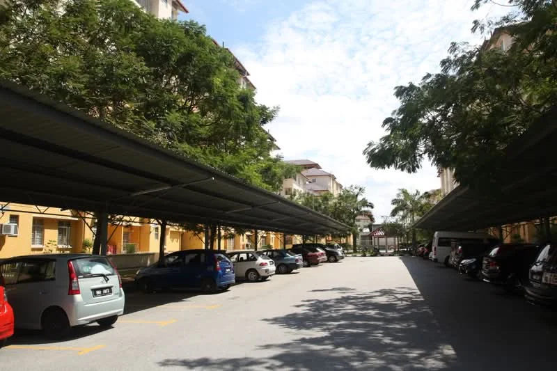 Exterior type: parking deck; features: covered parking, multiple parked cars, trees providing shade, concrete pavement, surrounding residential buildings, clear sky; style: modern.