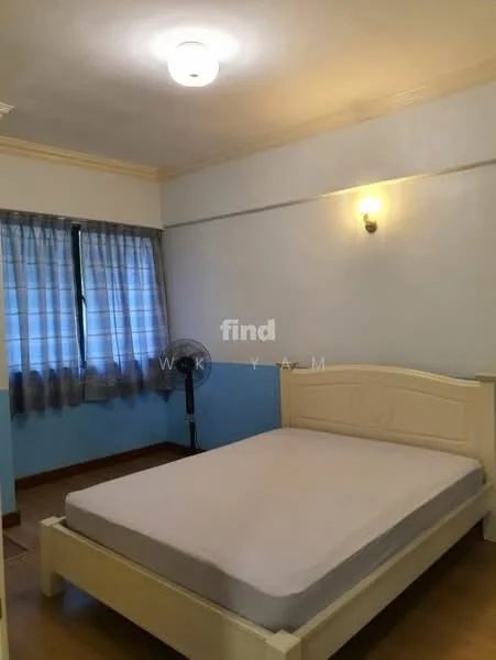 Bedroom features: light blue painted walls, cream painted ceiling, wooden flooring, single bed frame without mattress, floor-to-ceiling window with sheer curtains, wall-mounted light fixture, ceiling light, standing fan.