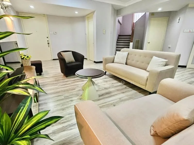 Living features: light grey fabric sofa, 2-seater beige sofa, 3-seater beige sofa, round coffee table with green base, dark brown armchair, light wood laminate flooring, decorative houseplants, wall-mounted TV unit, recessed ceiling lights, white painted walls, doorway leading to hallway, staircase visible in background; style: modern.
