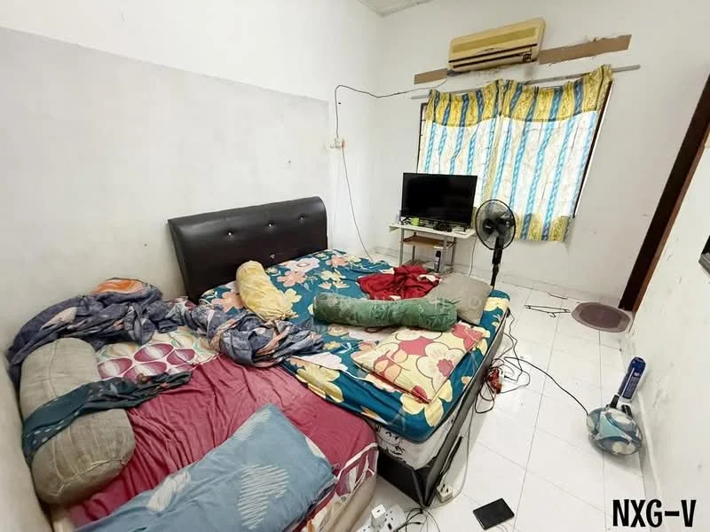 Bedroom features: queen-size bed with upholstered headboard, bedding with floral pattern, floor-to-ceiling window with sheer curtains, wall-mounted air conditioning unit, television on stand, standing fan, white tiled flooring, decorative throw pillows, cluttered bedside area with various items.