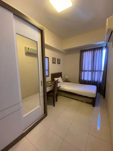 Bedroom features: single bed, upholstered headboard, bedside table, desk with chair, floor-to-ceiling window, sheer curtains, wall-mounted air conditioning unit, mirror sliding door wardrobe, white painted walls, tile flooring, ceiling light fixture; style: modern.