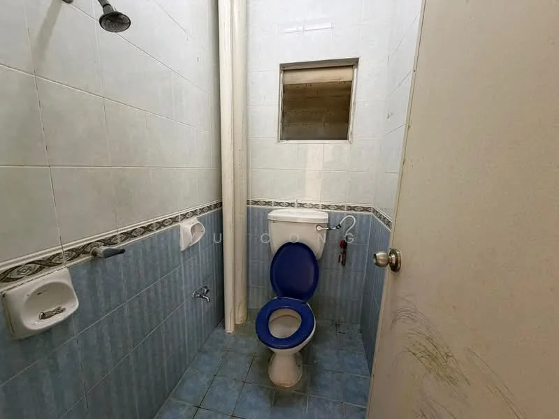Bathroom features: white tiled walls, blue tiled flooring, toilet with blue seat, wall-mounted faucet, shower head, window for ventilation, soap dish, toilet paper holder.