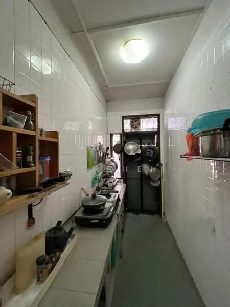 Kitchen features: white tiled walls, grey vinyl flooring, single-bowl stainless-steel sink, chrome pull-down faucet, wooden countertop, wall-mounted shelves, various cooking pots and utensils, kitchen appliances including a stove, metal door with security grill, overhead ceiling light; style: functional.