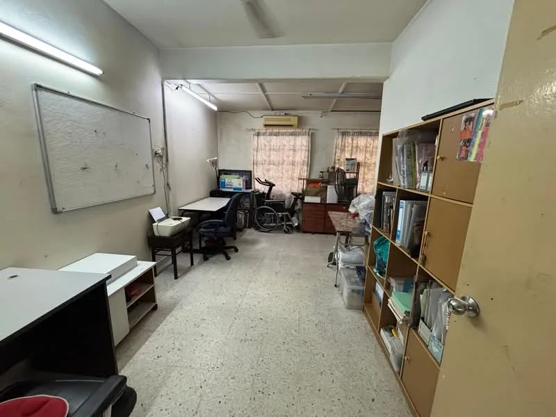Study features: white walls, tile flooring, ceiling light, window with sheer curtains, desk with chair, computer monitor, exercise bike, wooden storage cabinet, open shelving unit, whiteboard, cable management, wall-mounted air conditioning unit.